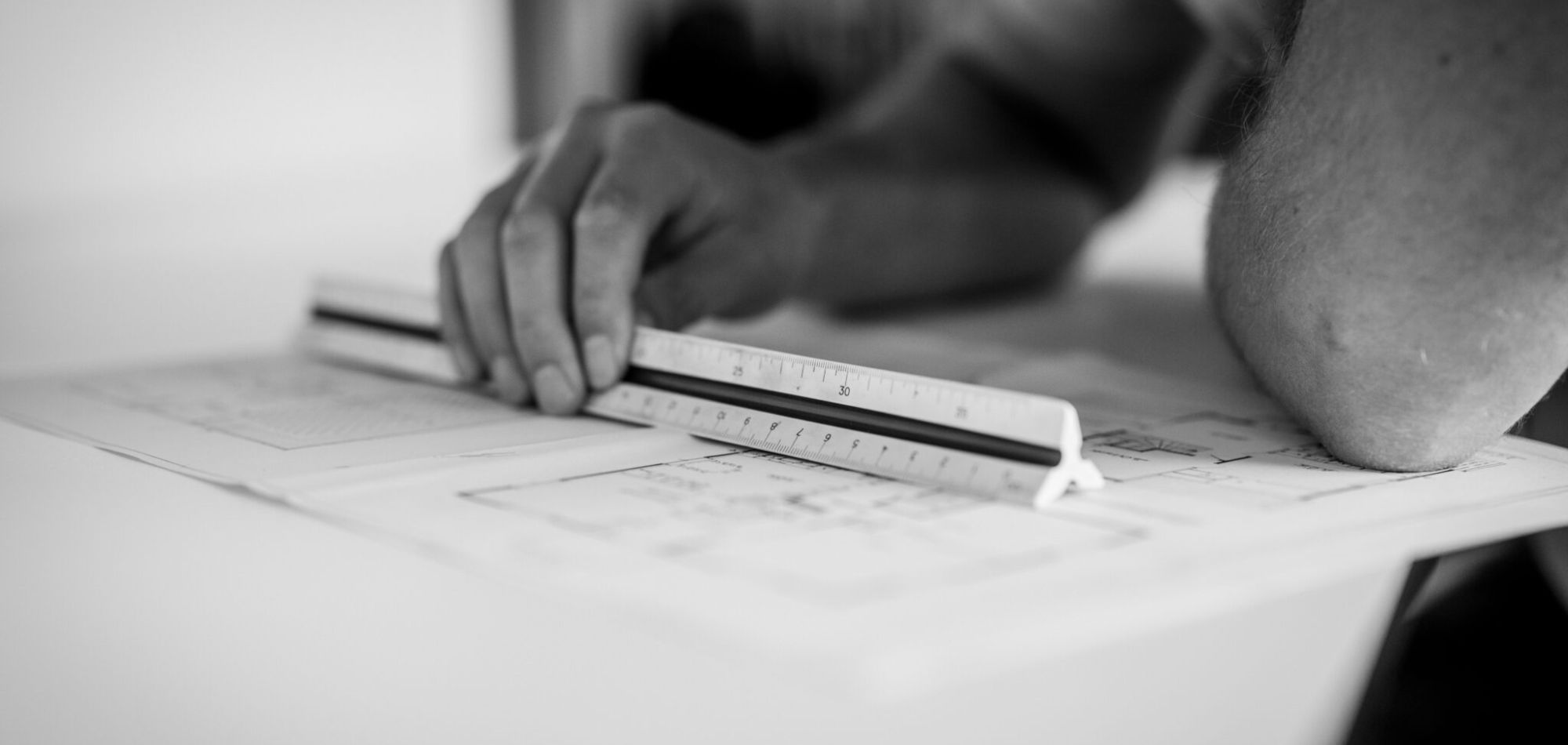 Hand med linjal som mäter på en ritning.