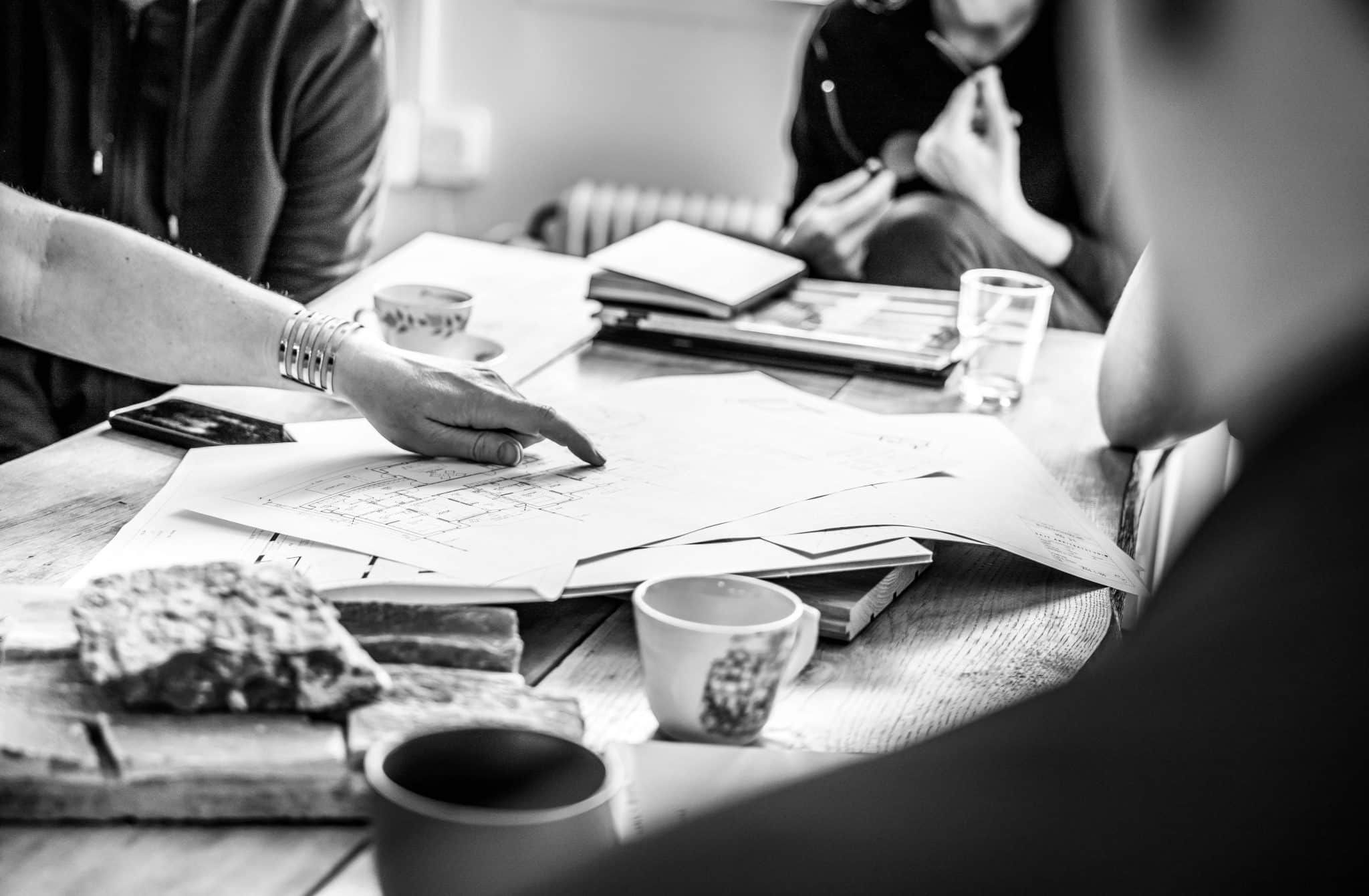 Personer runt ett bord som diskuterar en ritning.